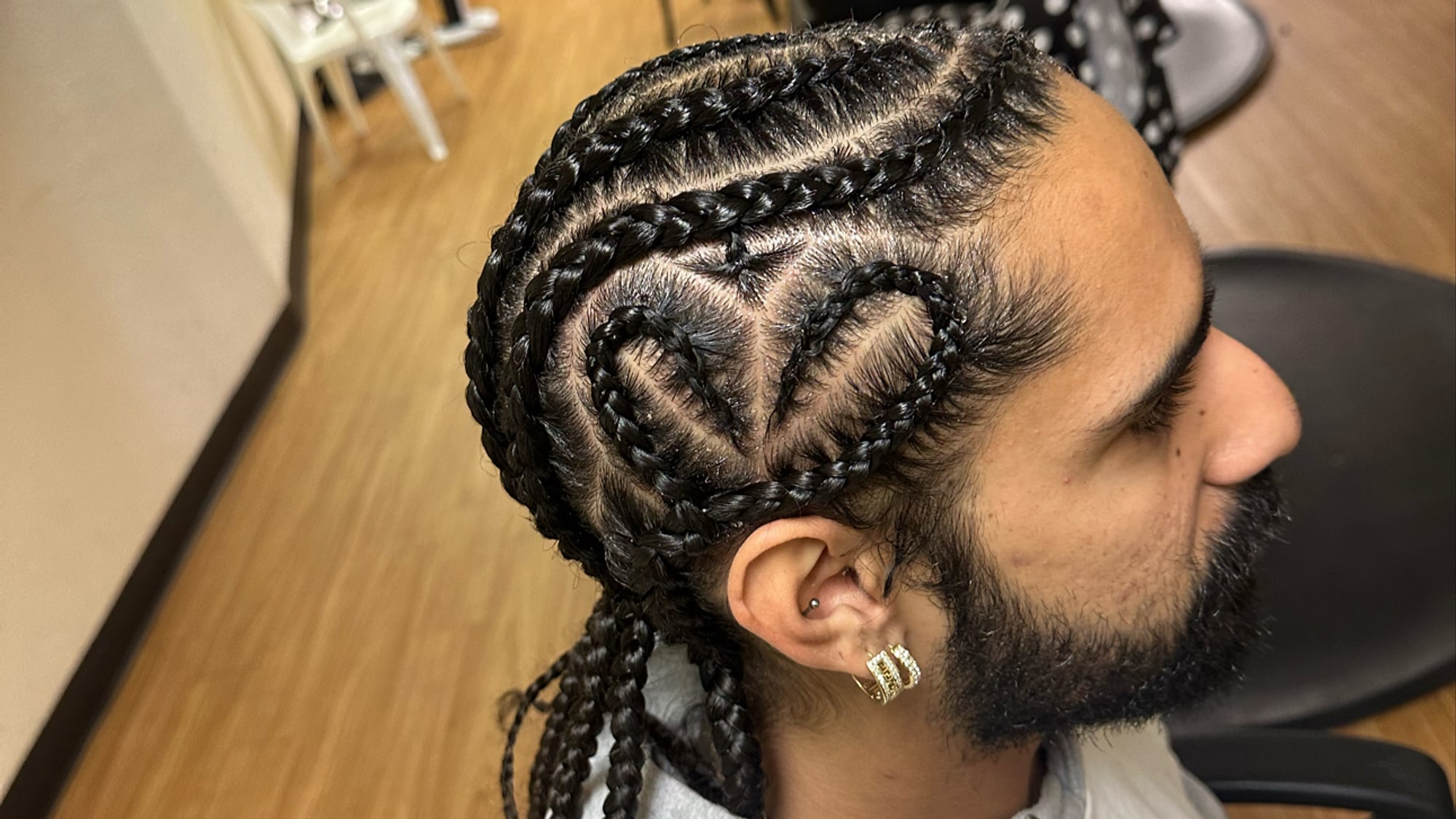 Cornrows braided into a heart design on a man, tapered at the sides