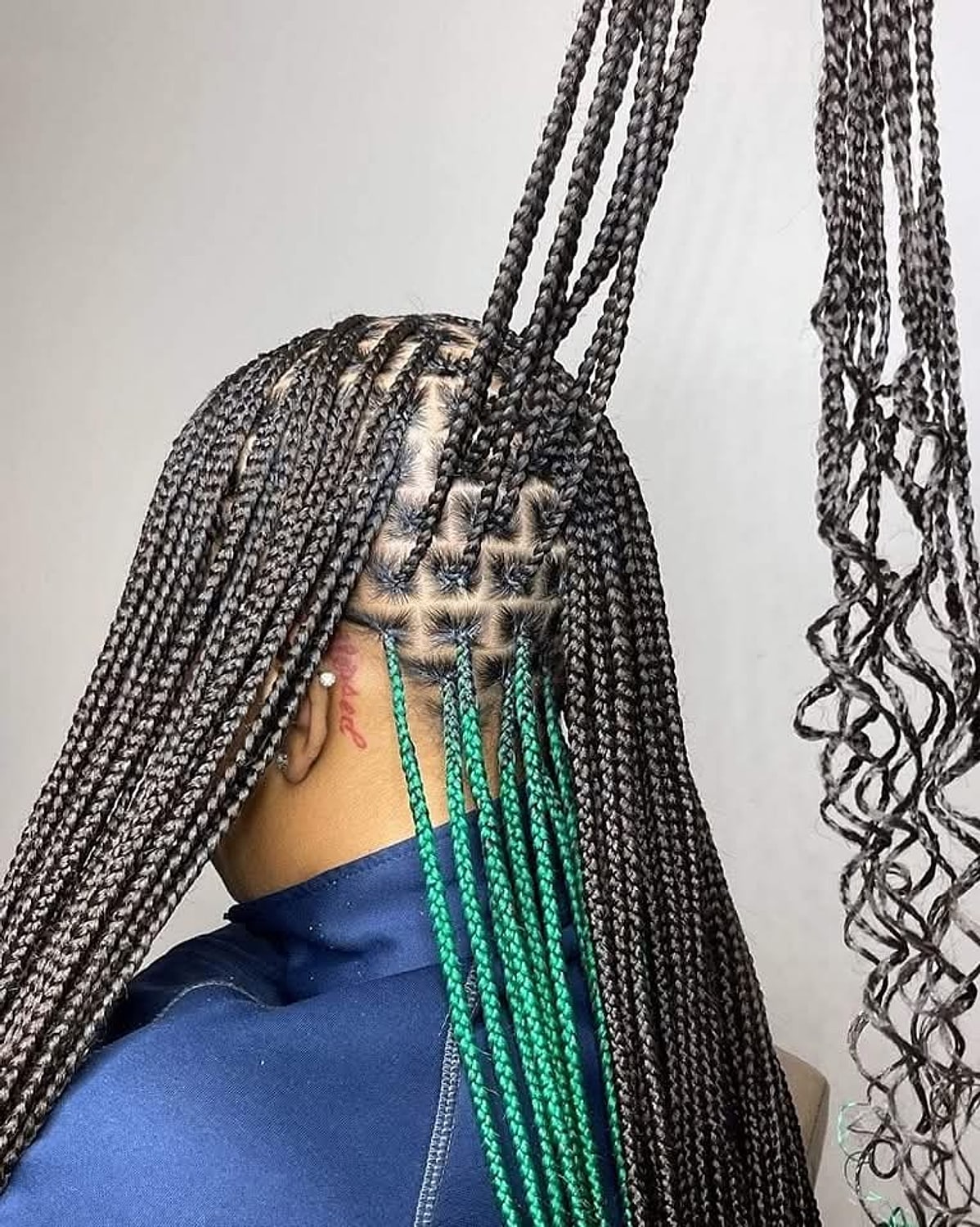 Long braids with green accent strands and curled ends